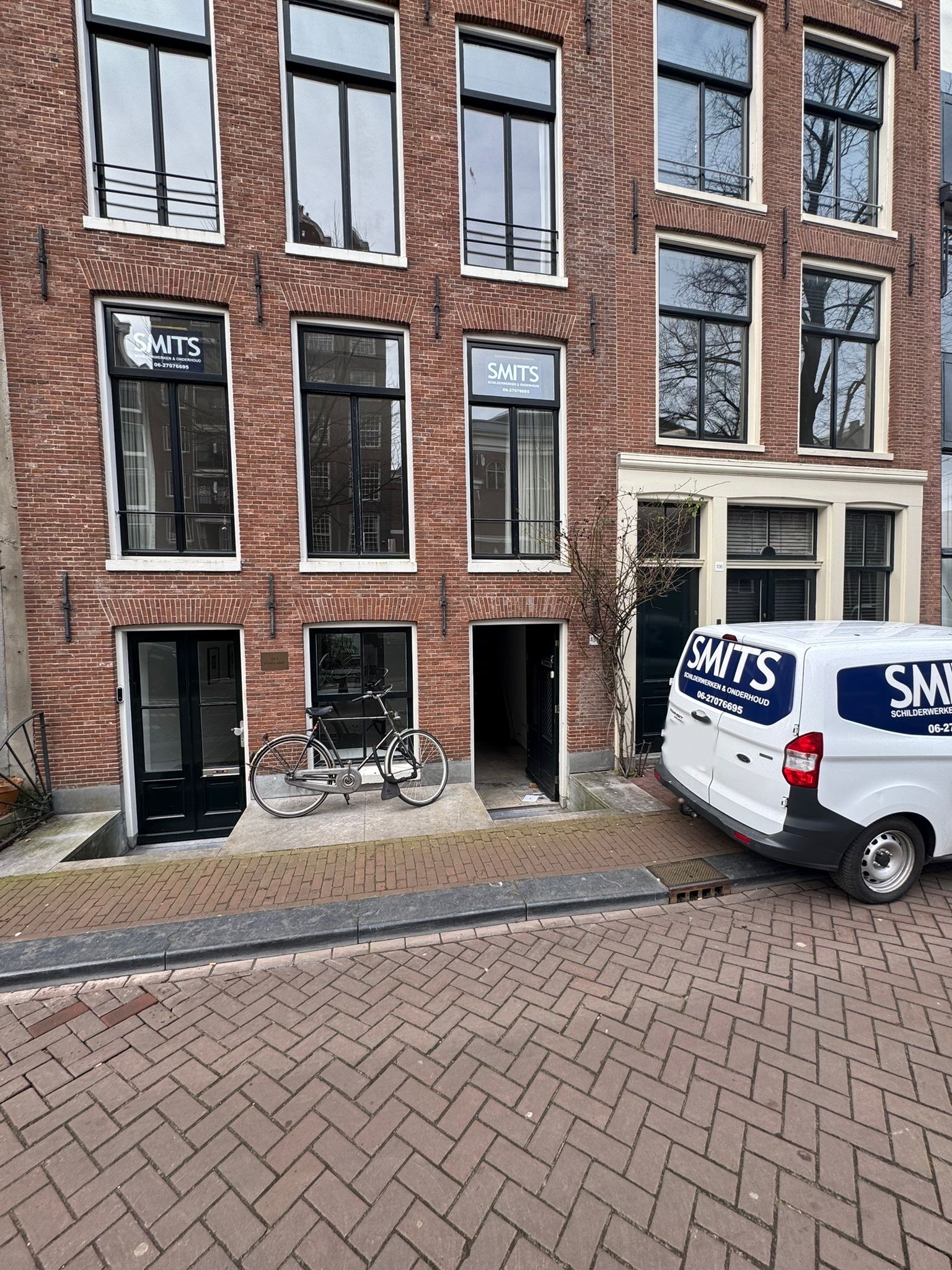De SMITS-bus voor een Amsterdams grachtenpand met SMITS-stickers in de ramen