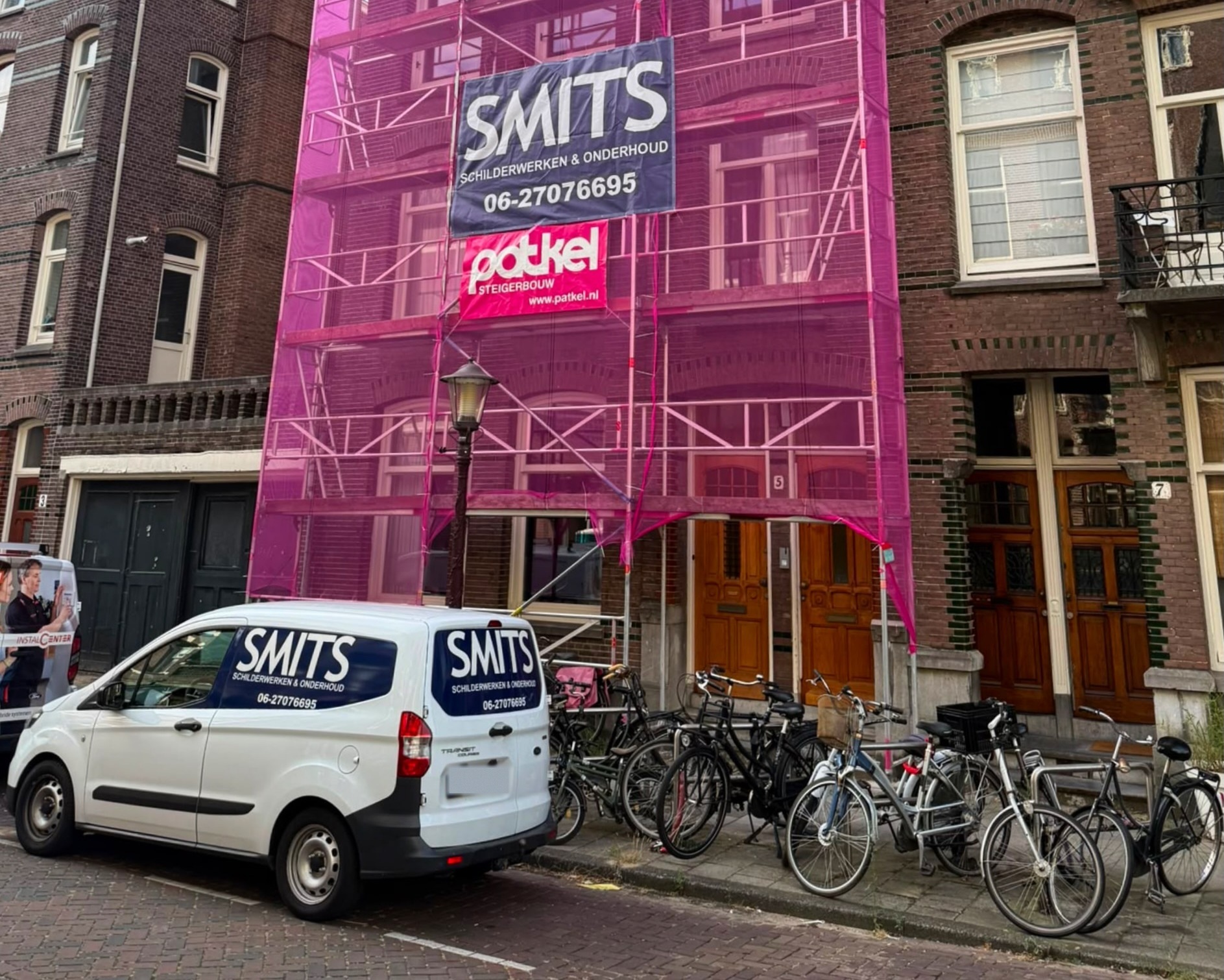 SMITS-banner aan de steiger van een Amsterdams pand, met de bedrijfsbus ervoor