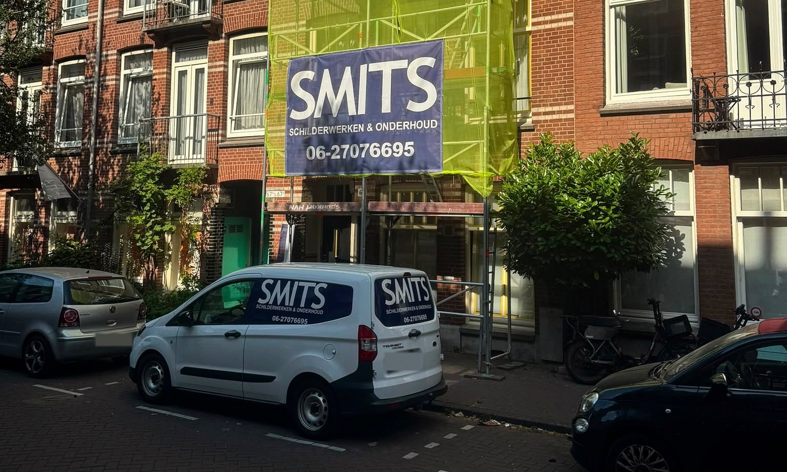 Schilderwerk aan een Amsterdams pand: steiger met SMITS-banner en de bedrijfsbus